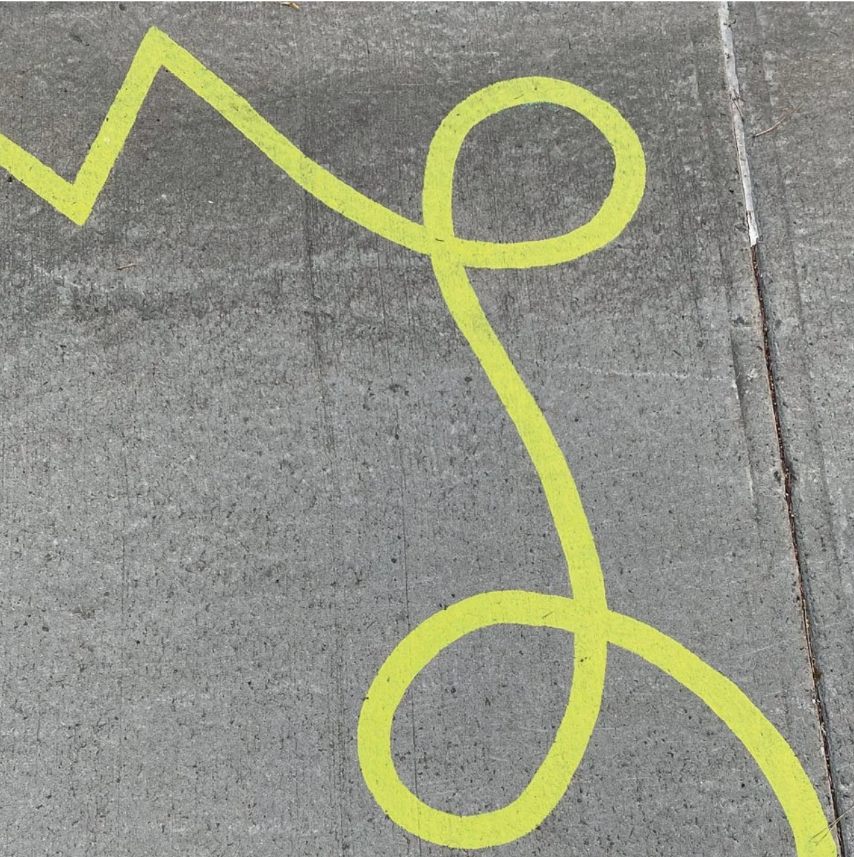 Dessin jaune en forme de personnage stylisé sur le béton