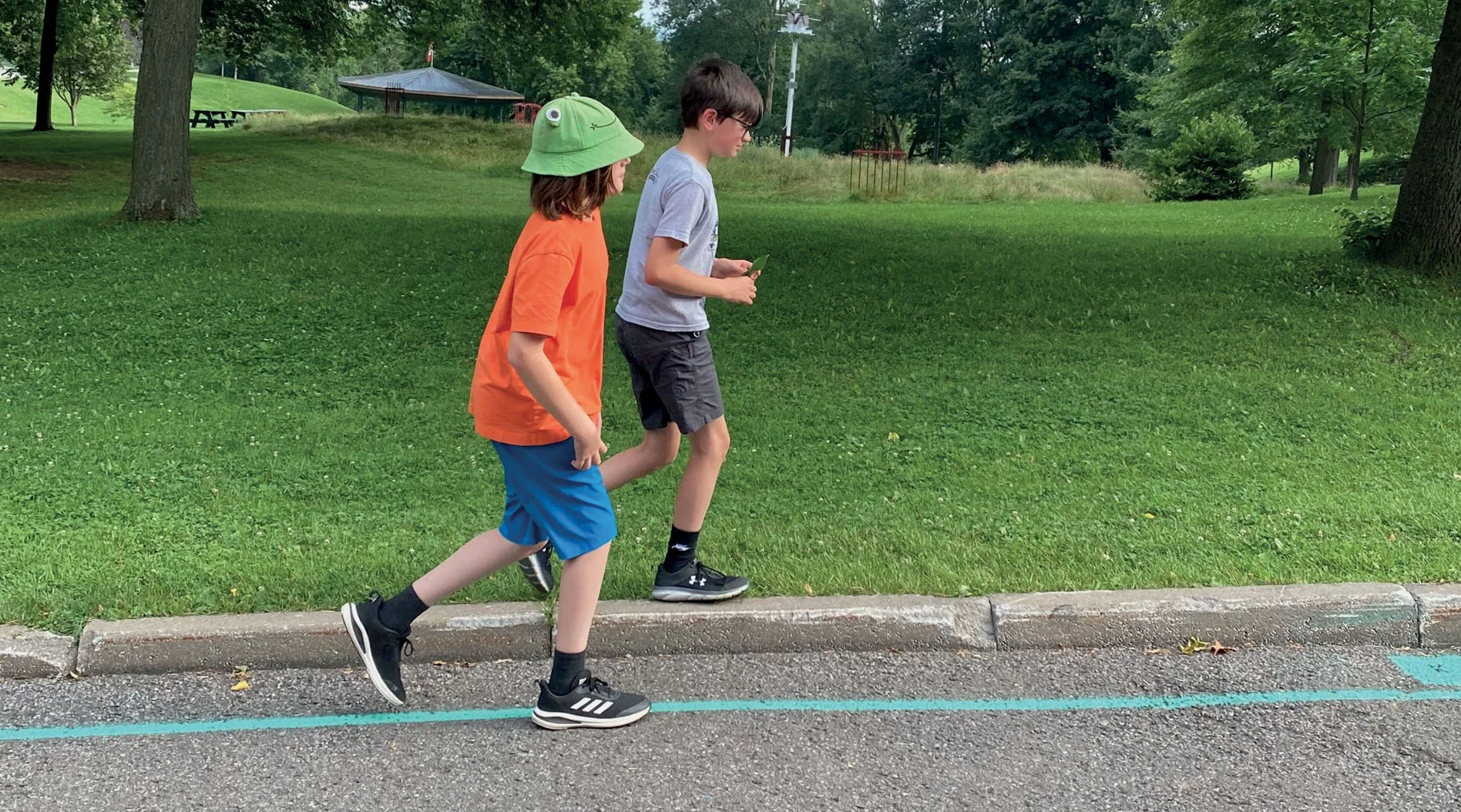 Les promenades urbaines du MNBAQ | deux enfants marchant le long d'un tracé turquoise au sol dans un parc